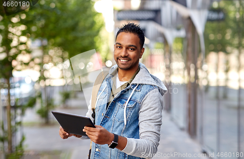 Image of man with tablet pc and backpack on city street