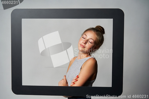 Image of Lovely girl standing behind digital tablet frame enjoying with closed eyes