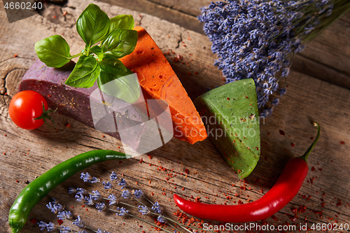 Image of Three different cheeses on rough wooden planks: lavender, paprika and pesto cheeses