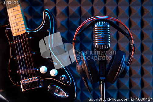 Image of Studio microphone with professional headphones and black electric guitar