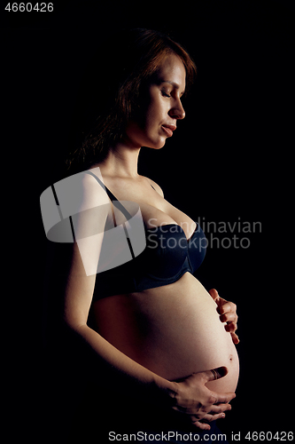 Image of Profile of pregnant woman over black background feeling calmness with closed eyes