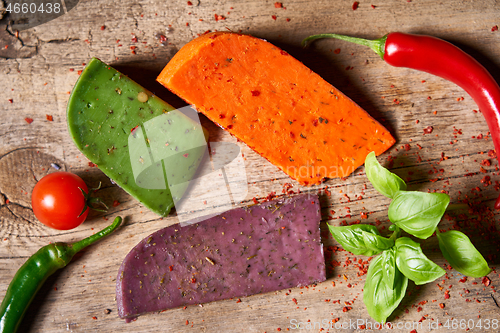 Image of Three different cheeses on rough wooden planks: lavender, paprik