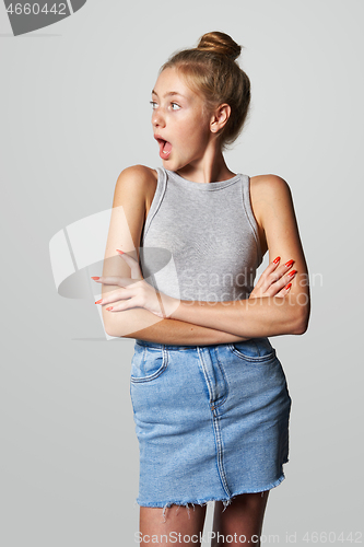 Image of Teen girl in denim skirt looking to side