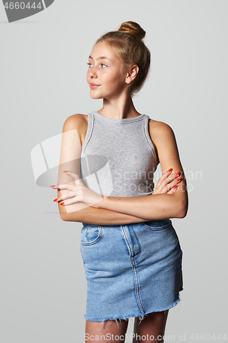 Image of Teen girl in denim skirt looking to side