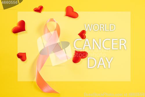 Image of the text world cancer day and a pink ribbon on a table background