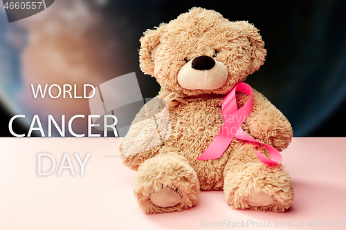 Image of the text world cancer day and a pink ribbon on a table background