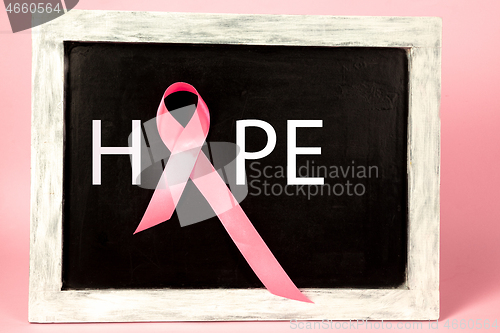 Image of the text world cancer day and a pink ribbon on a table background