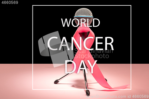 Image of the text world cancer day and a pink ribbon on a table background