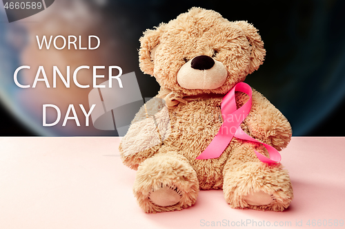 Image of the text world cancer day and a pink ribbon on a table background