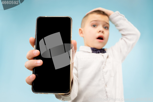 Image of Indoor portrait of attractive young boy holding blank smartphone