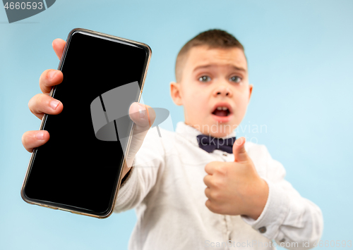 Image of Indoor portrait of attractive young boy holding blank smartphone