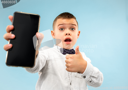 Image of Indoor portrait of attractive young boy holding blank smartphone