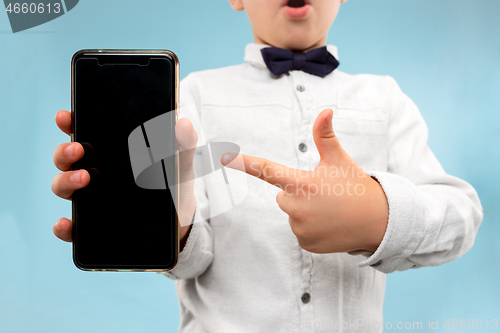 Image of Indoor portrait of attractive young boy holding blank smartphone