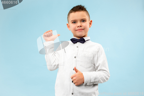 Image of The happy teen boy standing and smiling against blue background.