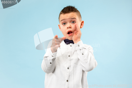 Image of The teen boy whispering a secret behind her hand over blue background