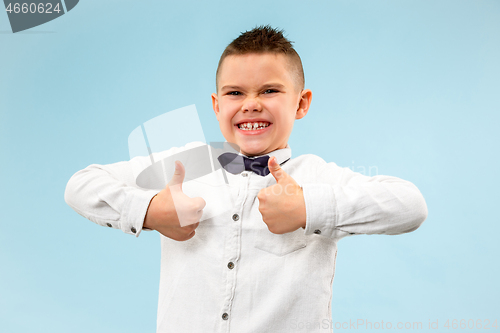 Image of The happy teen boy standing and smiling against blue background.