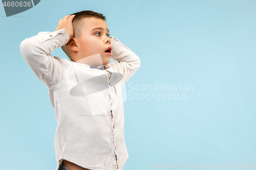 Image of The young attractive teen boy looking suprised isolated on blue