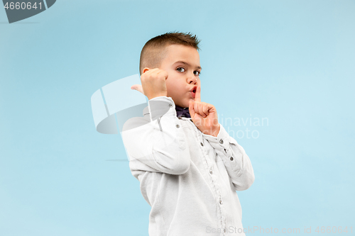 Image of The teen boy whispering a secret behind her hand over blue background