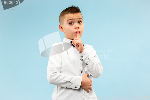 Image of The teen boy whispering a secret behind her hand over blue background