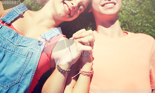 Image of happy teenage couple lying on grass at summer