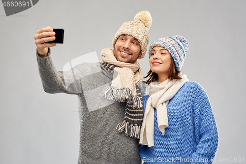 Image of couple in winter hats taking selfie by smartphone