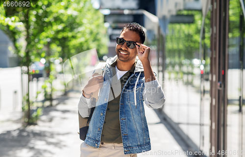 Image of indian man in sunglasses with backpack in city