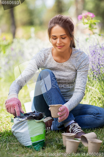 Image of woman filling pots with soil at summer garden