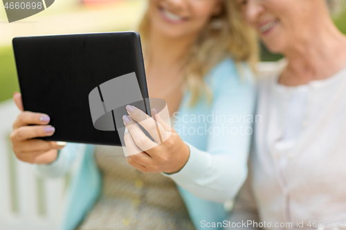 Image of adult daughter and senior mother with tablet pc