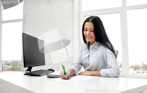Image of businesswoman writing to notebook at office
