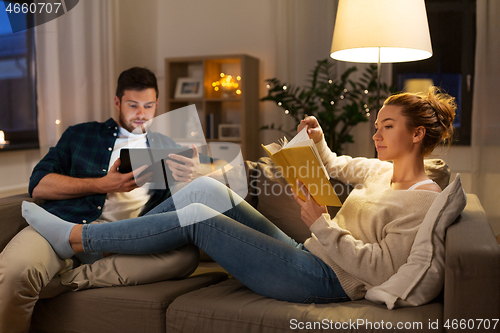 Image of couple with tablet computer and book at home