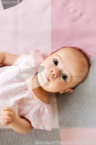 Image of sweet baby girl lying on knitted blanket