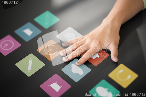 Image of hand using interactive panel with app icons on it