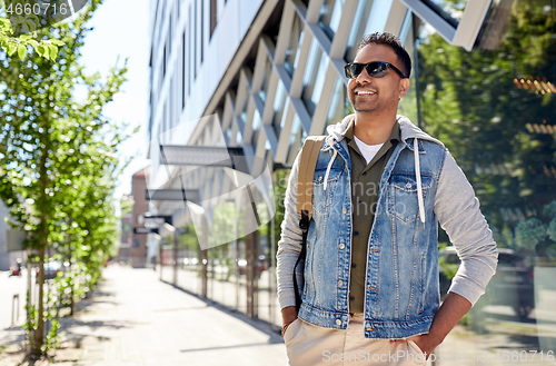 Image of indian man with backpack walking along city street