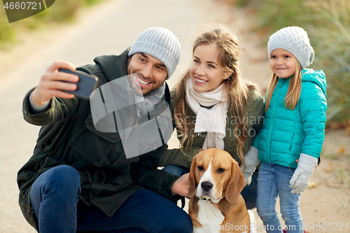 Image of happy family with dog taking selfie in autumn