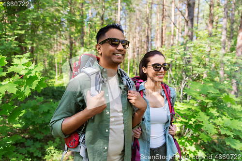 Image of mixed race couple with backpacks hiking in forest