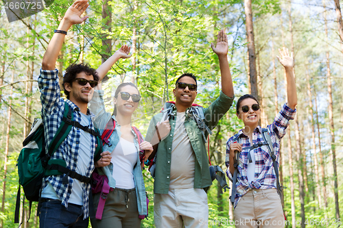 Image of group of friends with backpacks hiking in forest