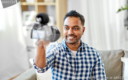 Image of male video blogger with camera blogging at home