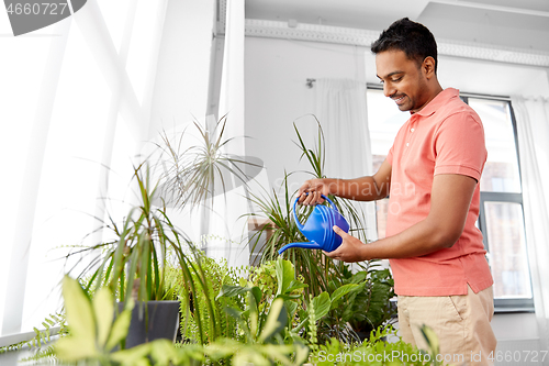 Image of indian man watering houseplants at home