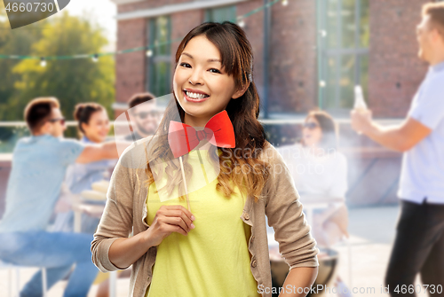 Image of happy asian woman with bow tie over rooftop party