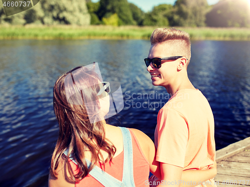 Image of happy teenage couple sitting on river berth