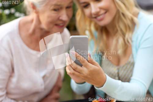 Image of daughter and senior mother taking selfie at park