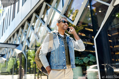 Image of man with backpack calling on smartphone in city