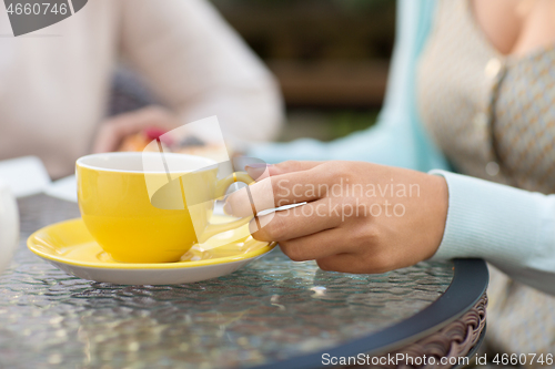 Image of hand of woman drinking tea at outdoor cafe