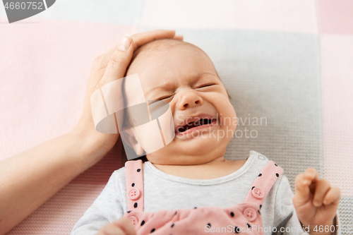 Image of mother\'s hand touching crying little baby daughter