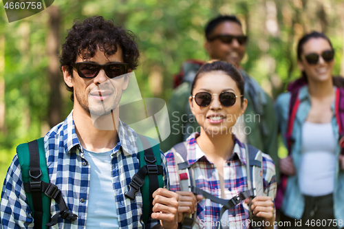 Image of group of friends with backpacks hiking in forest