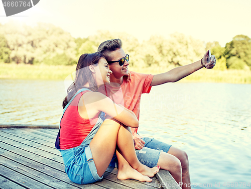 Image of happy teenage couple taking selfie on smartphone