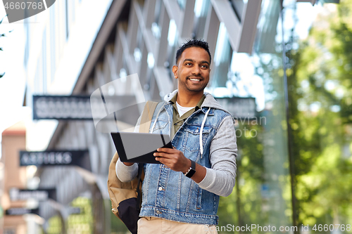 Image of man with tablet pc and backpack on city street