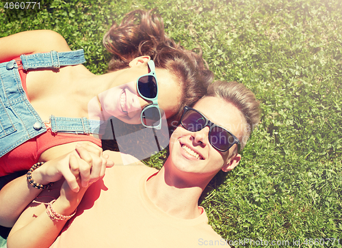 Image of happy teenage couple lying on grass at summer