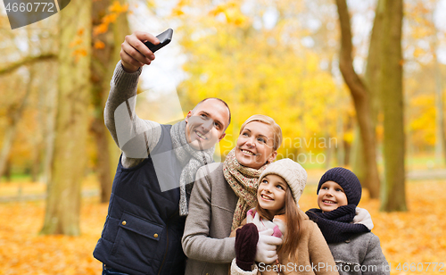 Image of happy family with camera in autumn park