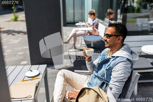 Image of indian man drinking coffee at city street cafe